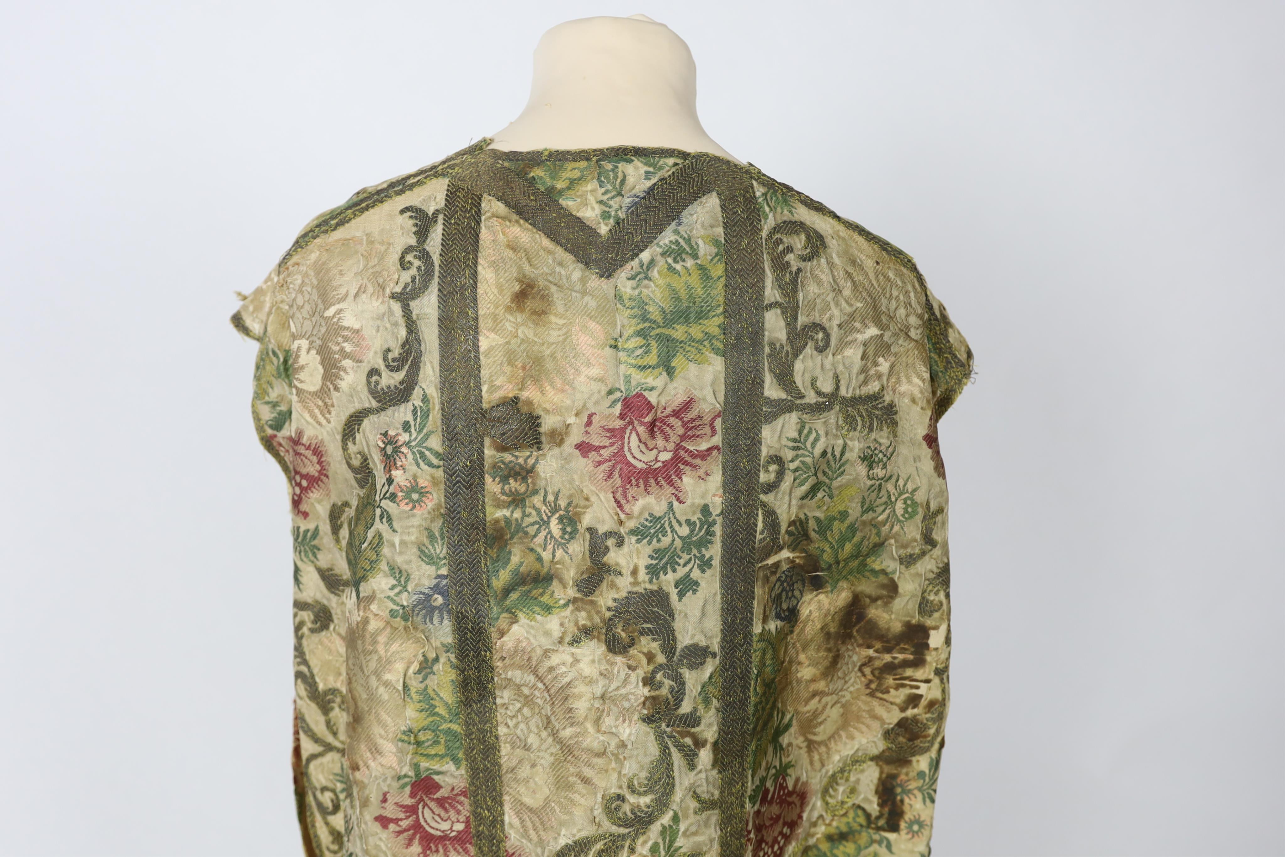 A late 18th century continental, possibly French, silk multi coloured and metallic brocade chasuble, lined with thick linen, edged and panelled with a thick metallic braid, 99cm long